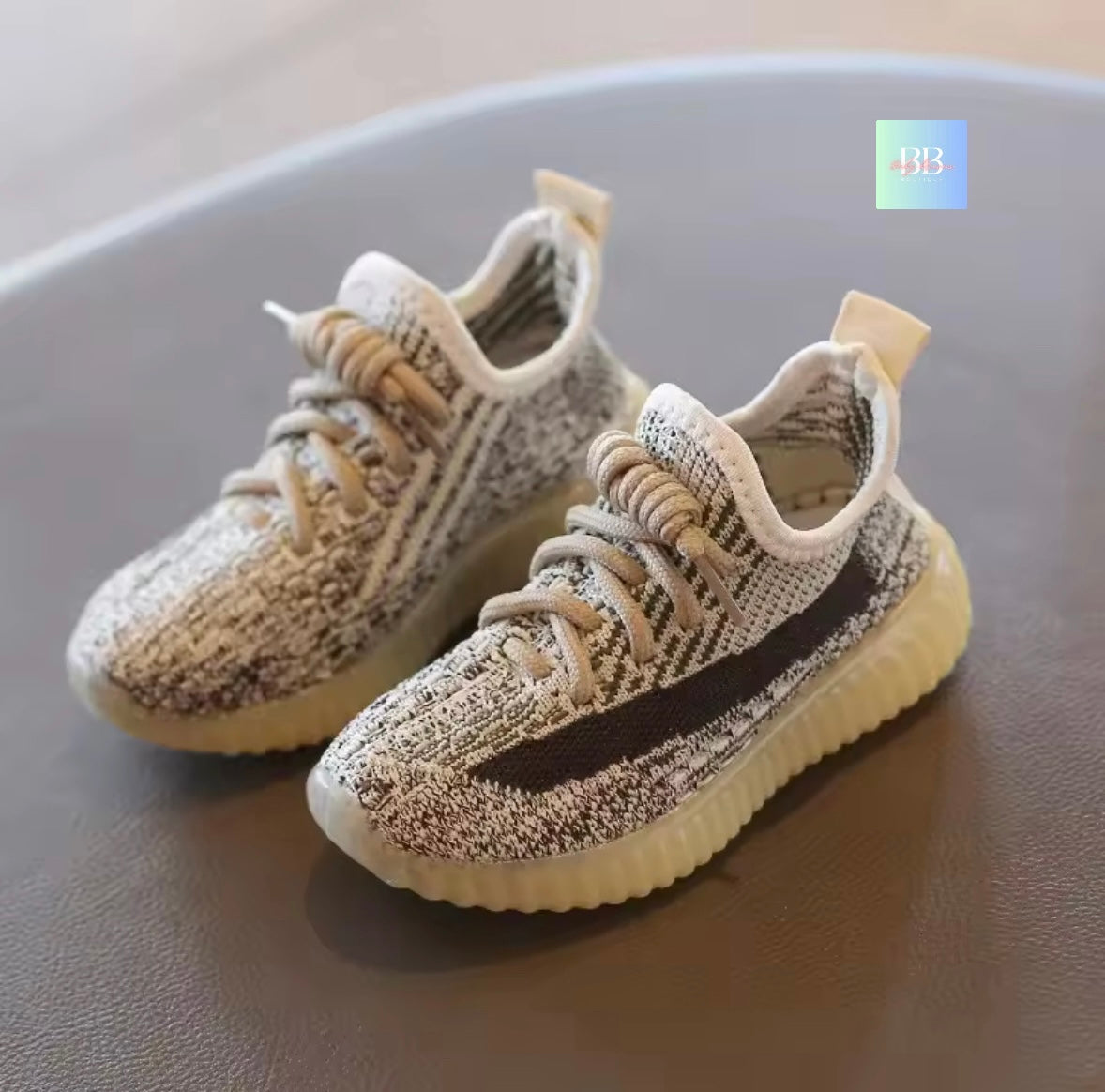 Pair of baby shoes with textured design on a reflective surface