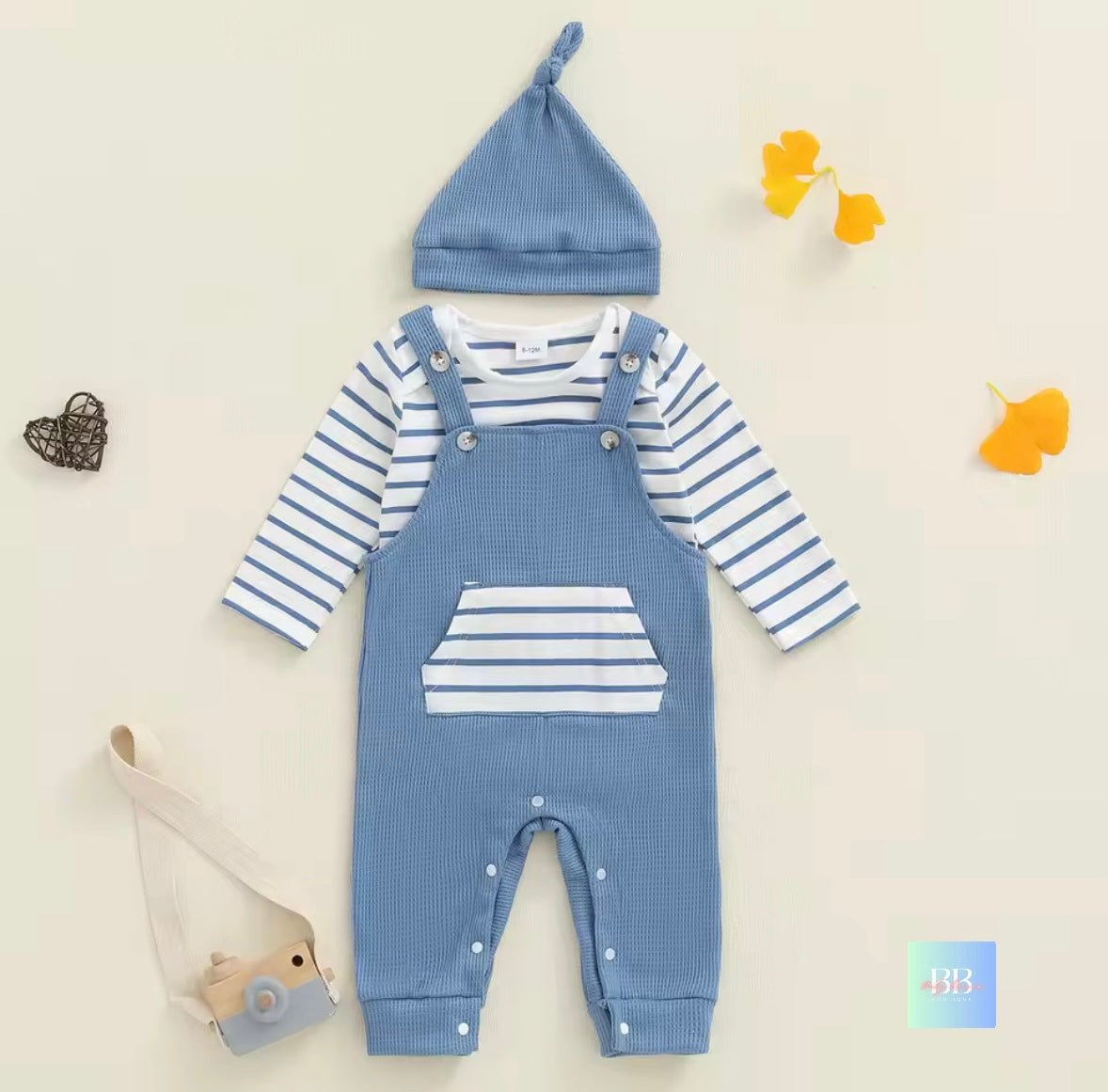 Baby outfit with blue and white striped shirt, bib overalls, and matching hat on a light beige background.