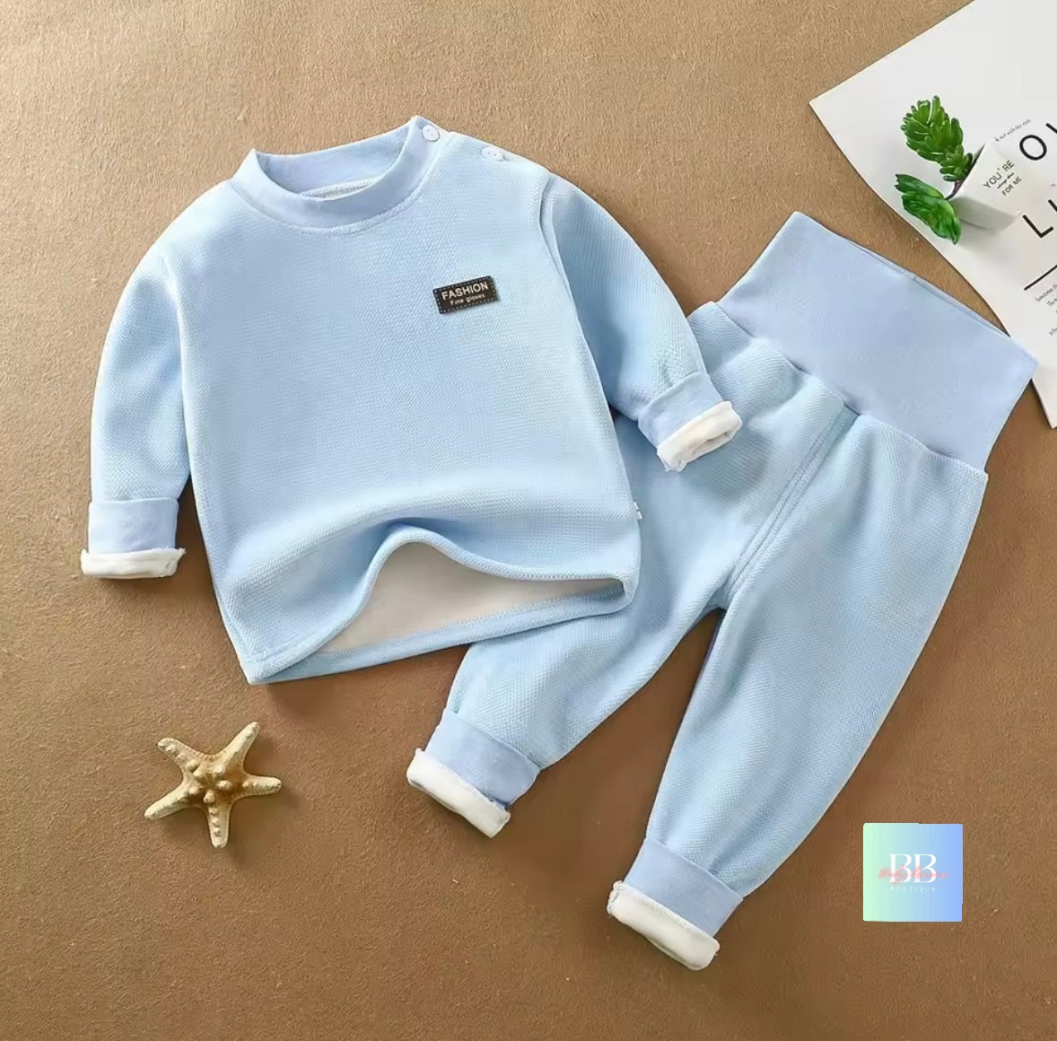 Children's light blue fleece set with white cuffs on a brown surface