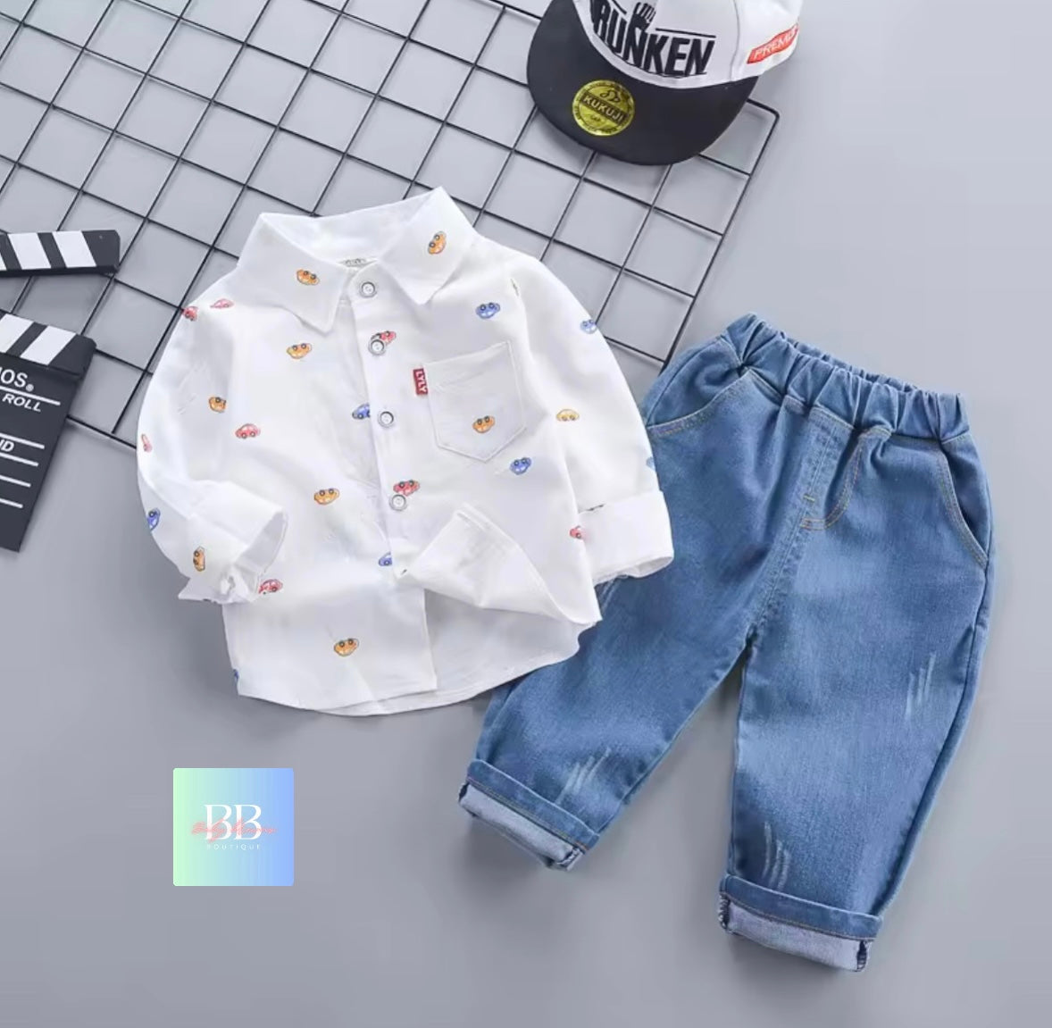 White shirt with colorful patterns and blue jeans on a gray background