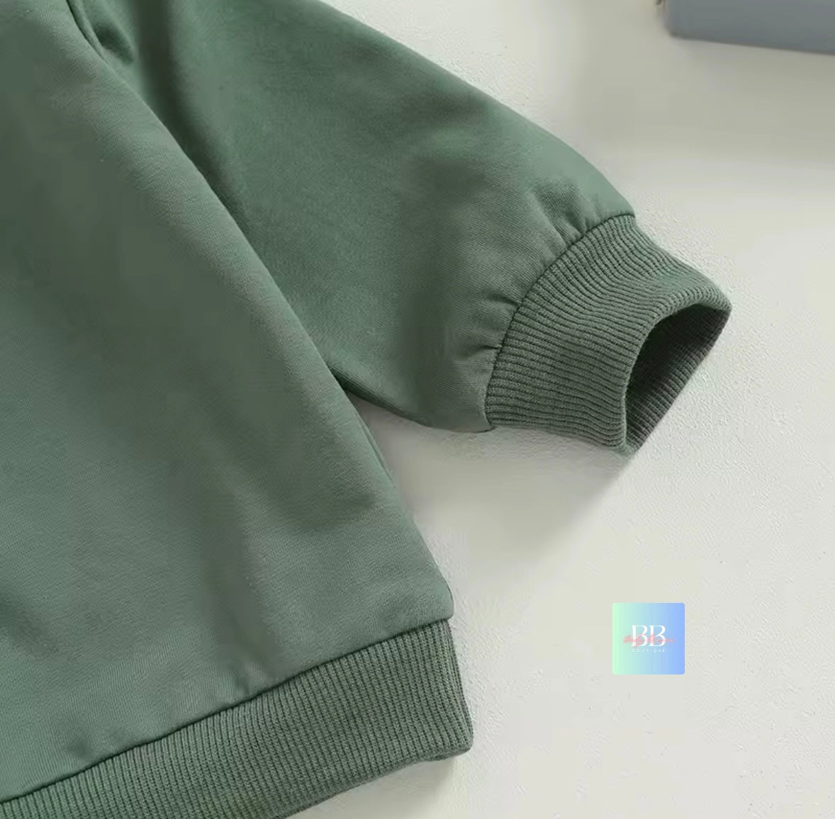 Green sweatshirt sleeve on a light gray background