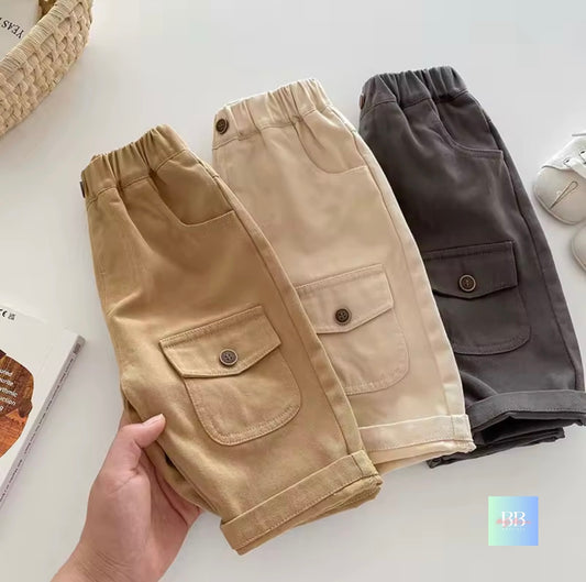 Three pairs of cargo pants in beige, brown, and gray on a white surface.