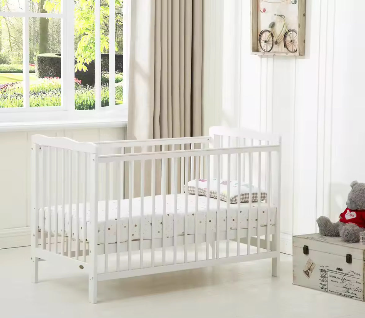 White crib in a bright room with a window and decorative elements.