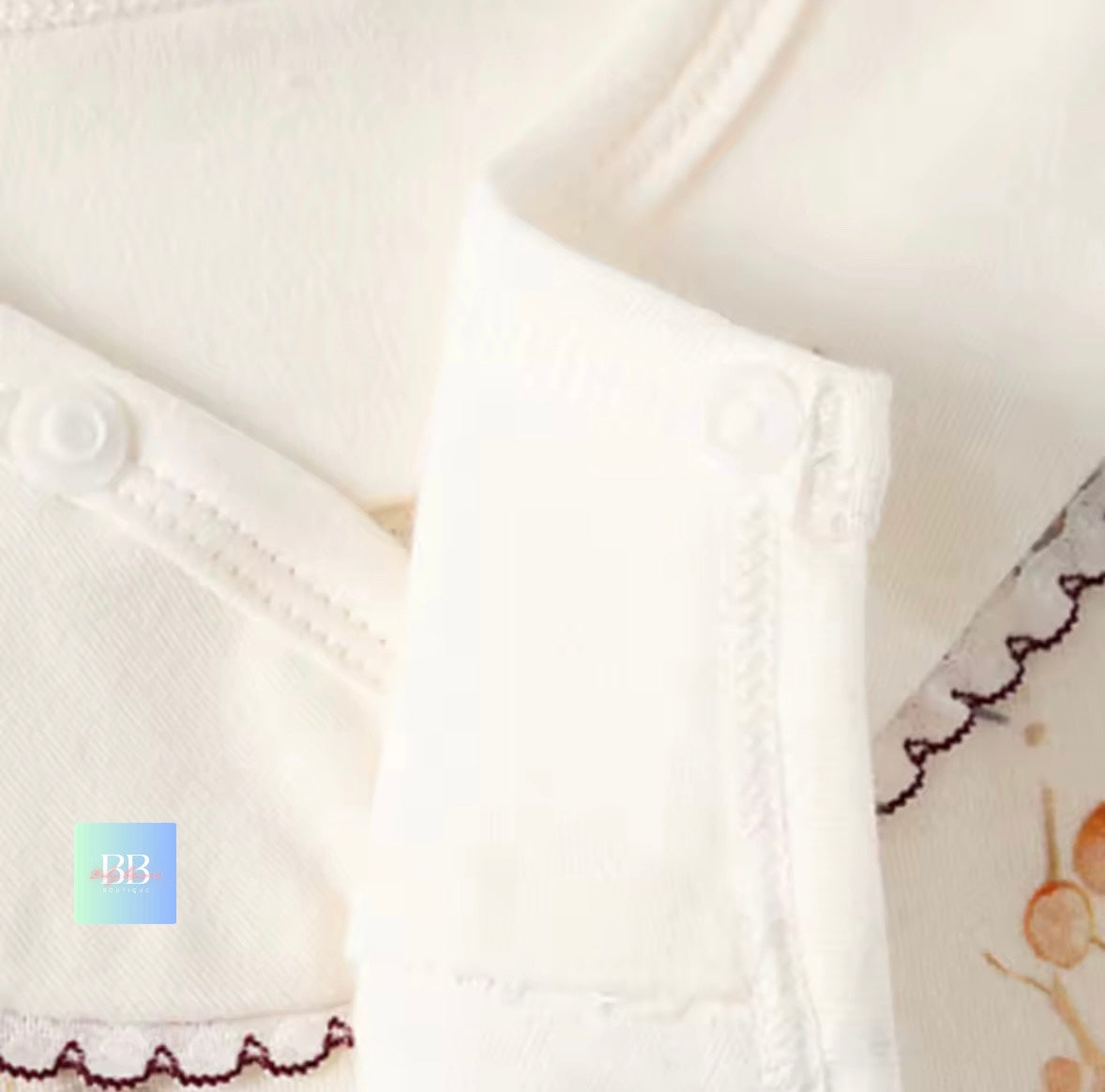 Close-up of a white garment with lace trim and a brand logo in the corner.