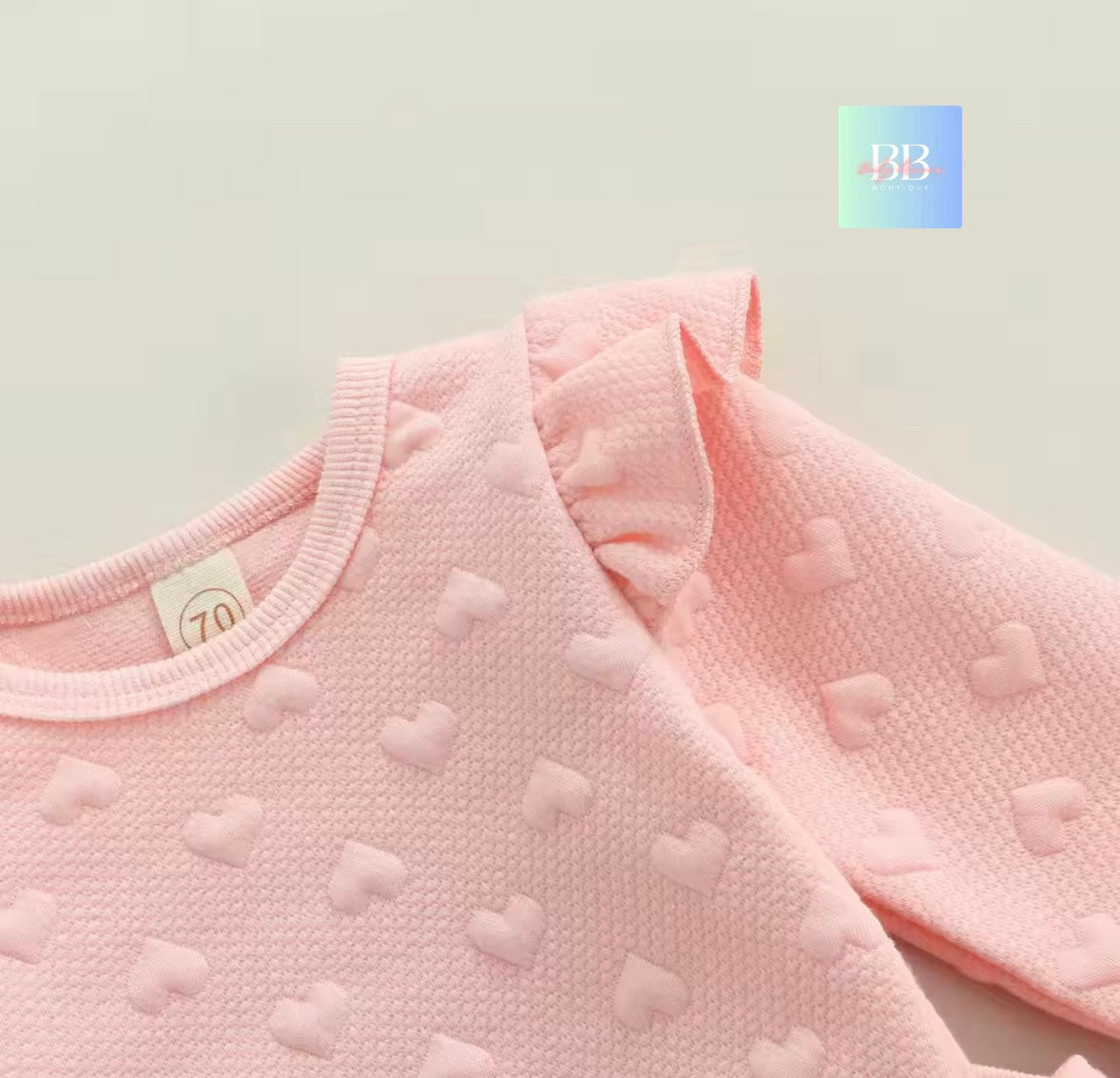 Close-up of a pink baby bib with heart patterns on a light background