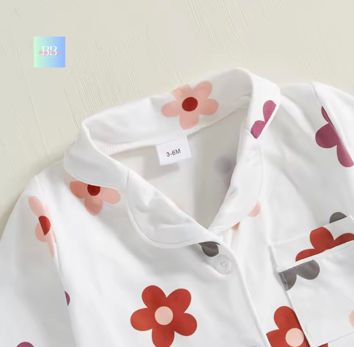 White baby outfit with floral patterns on a light background