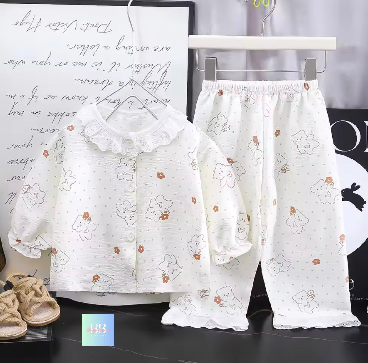 White floral pajama set on a black surface with text and shoes in the background