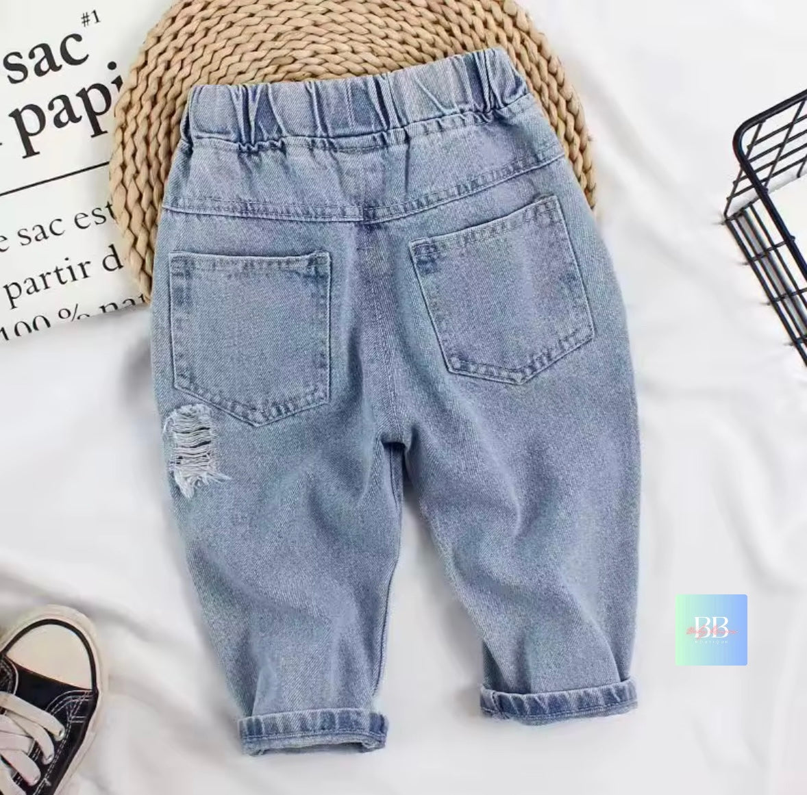 Light blue denim jeans with a distressed back pocket on a white background