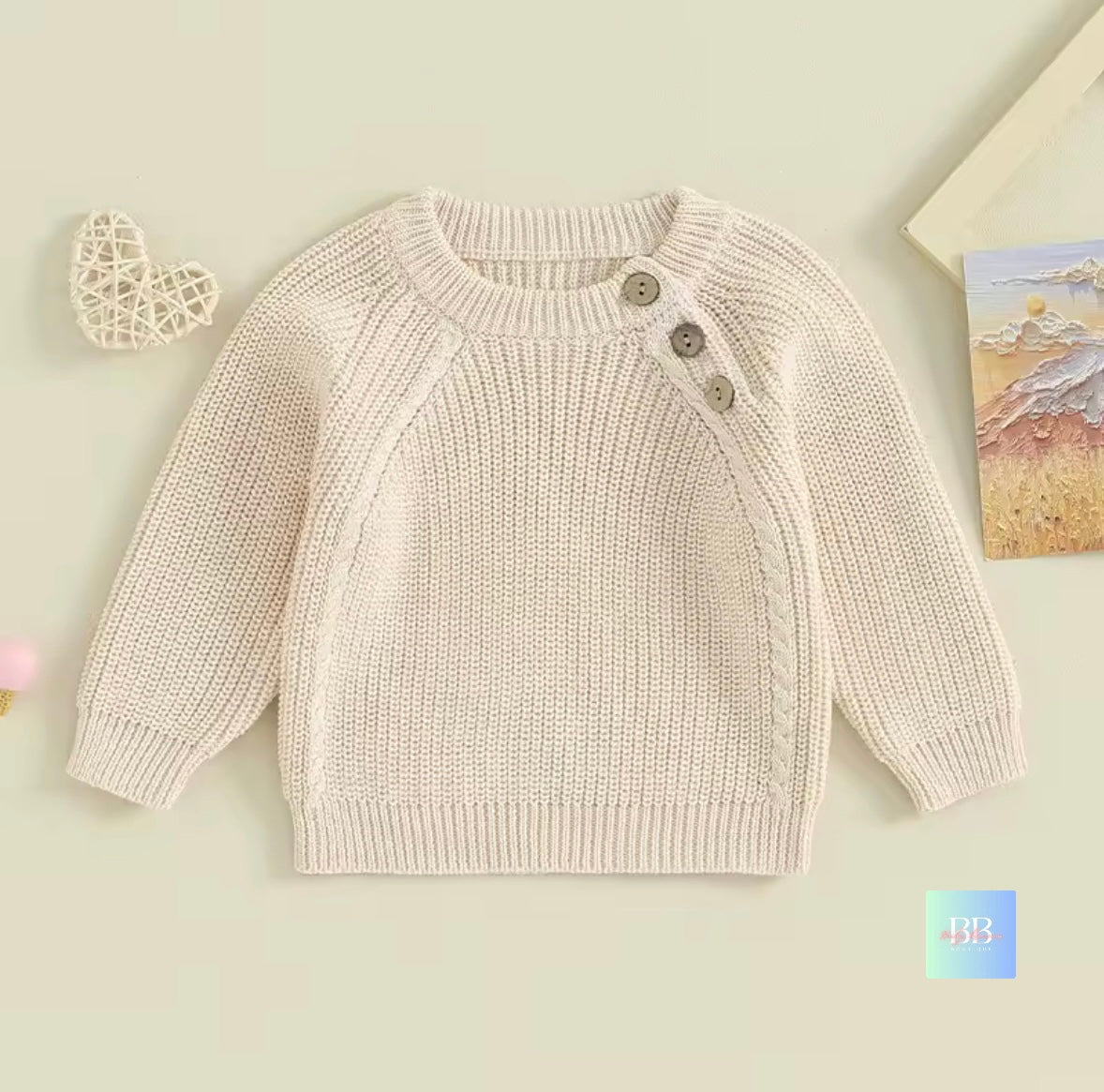Knitted baby sweater with buttons on a light background