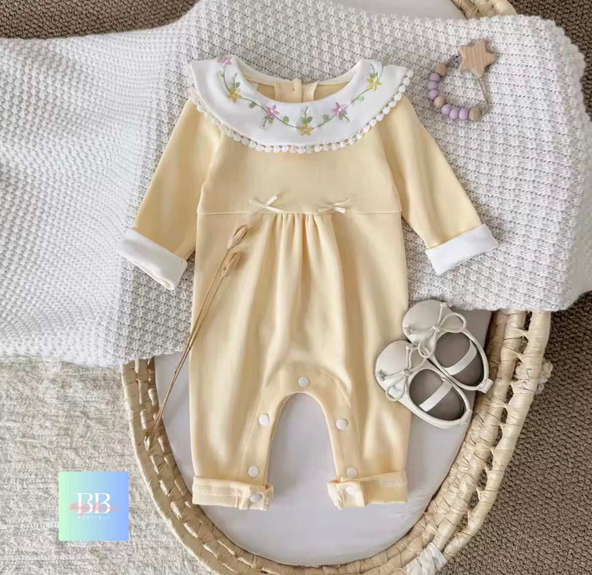 Baby romper with floral collar on a textured surface