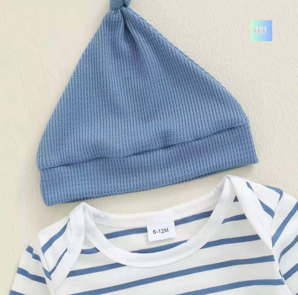 Blue baby hat and striped baby shirt on a light background