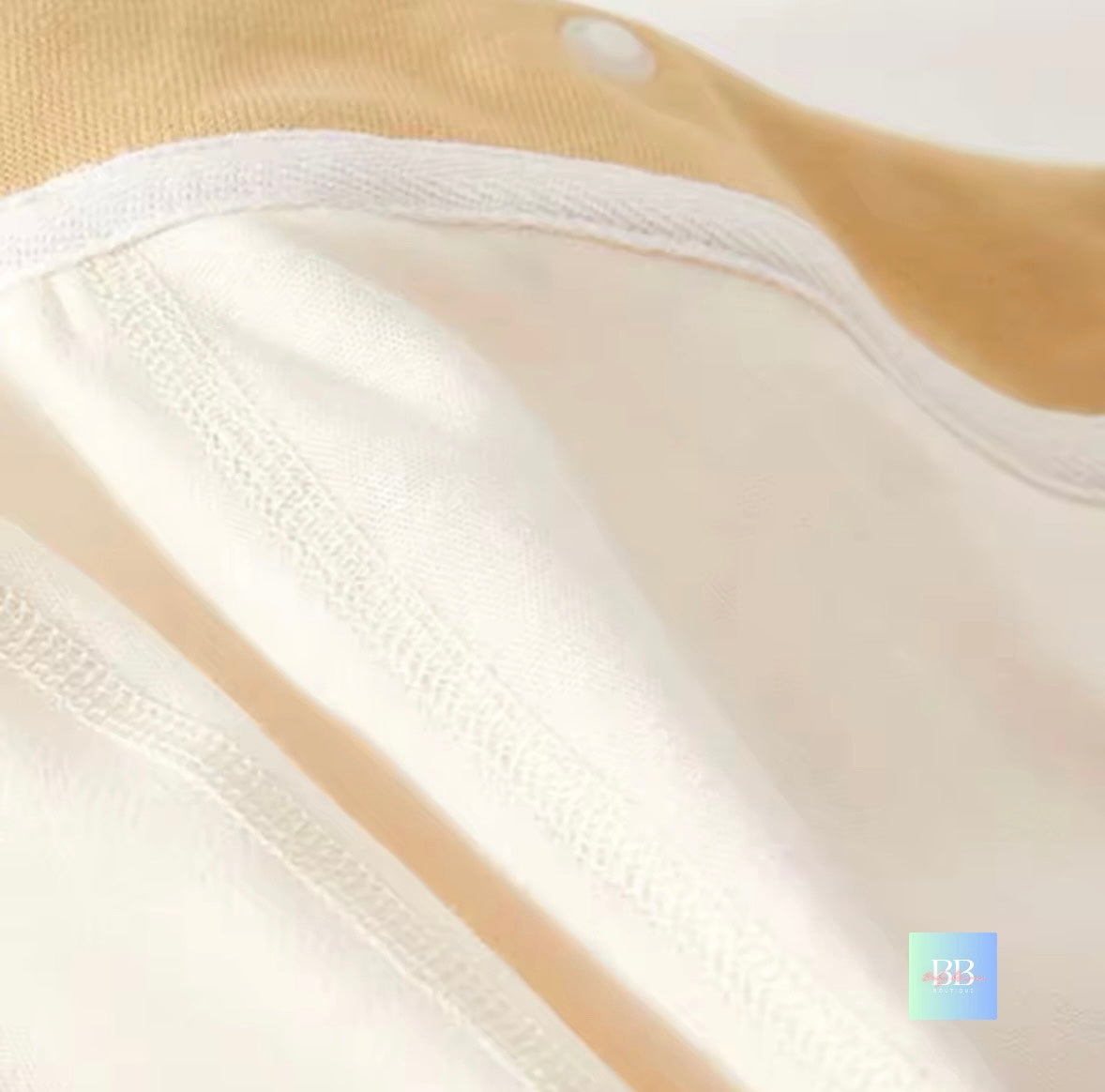 Close-up of beige and white fabric with a brand logo in the corner.