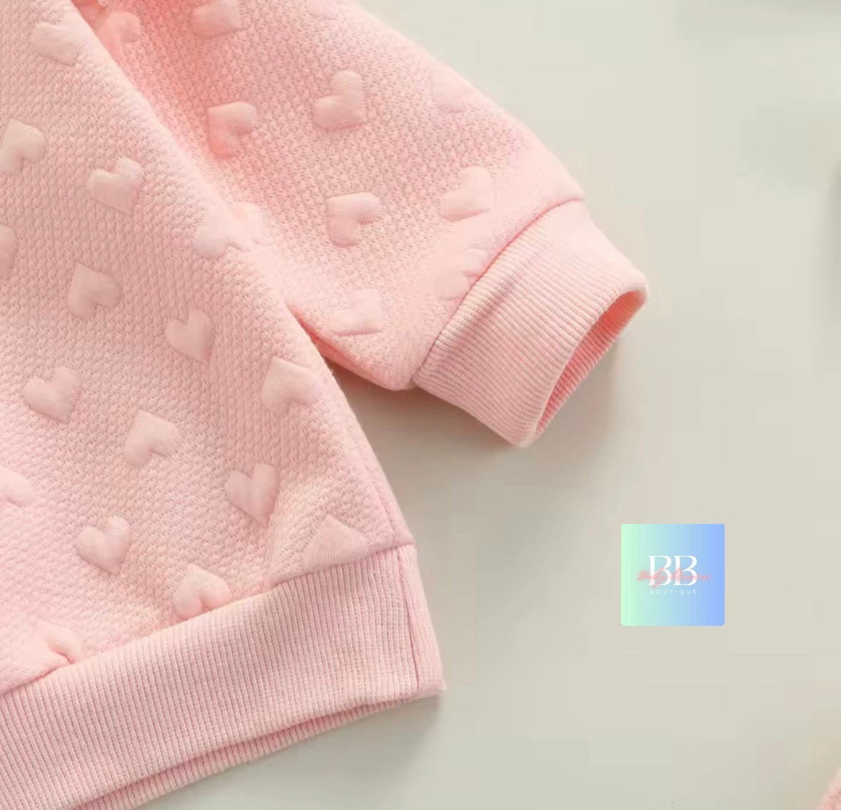 Pink textured fabric with heart patterns on a light gray background