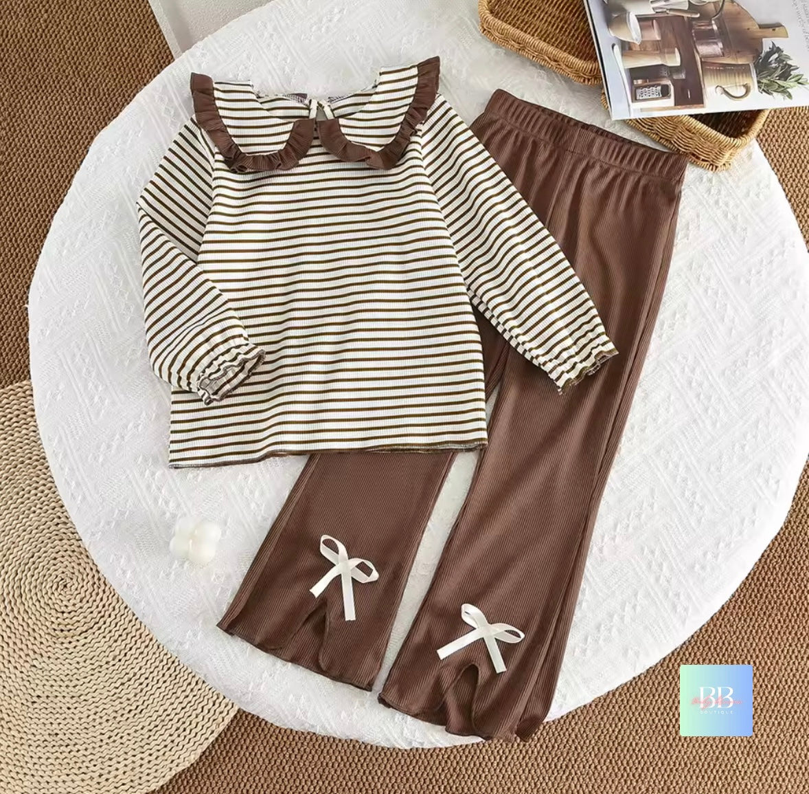 Children's outfit with striped shirt and brown pants on a white surface