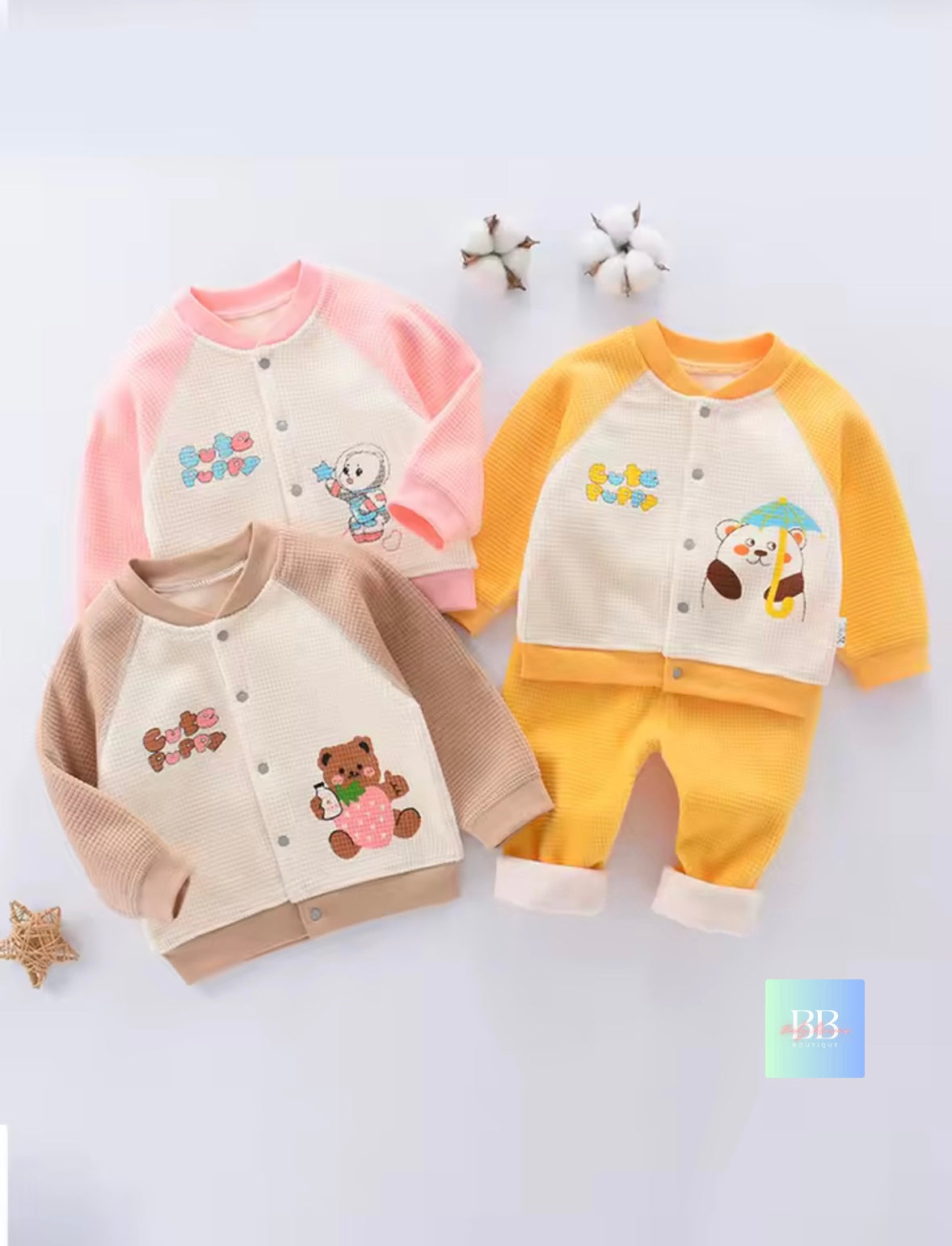 Three children's outfits with teddy bear designs on a light gray background