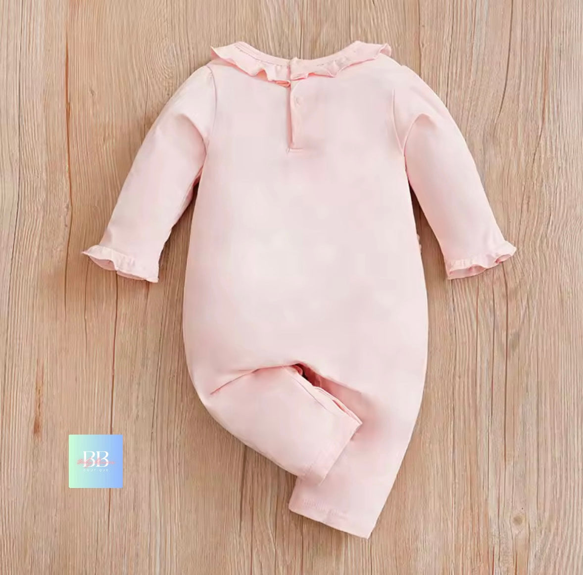 Pink baby onesie on a wooden surface