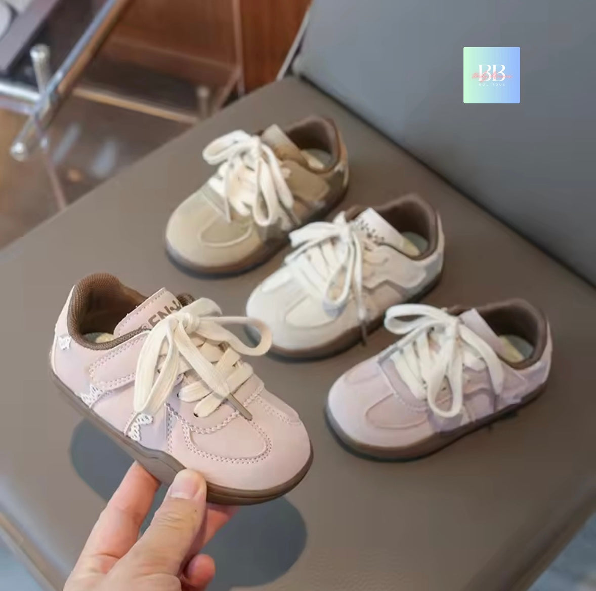 Set of children's shoes on a kitchen counter with a hand holding one shoe.