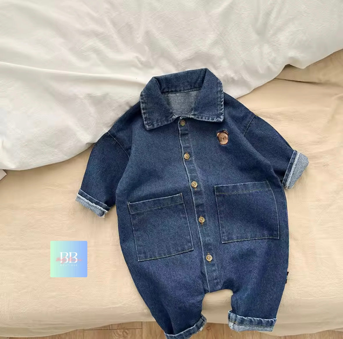 Blue denim baby romper on a beige surface