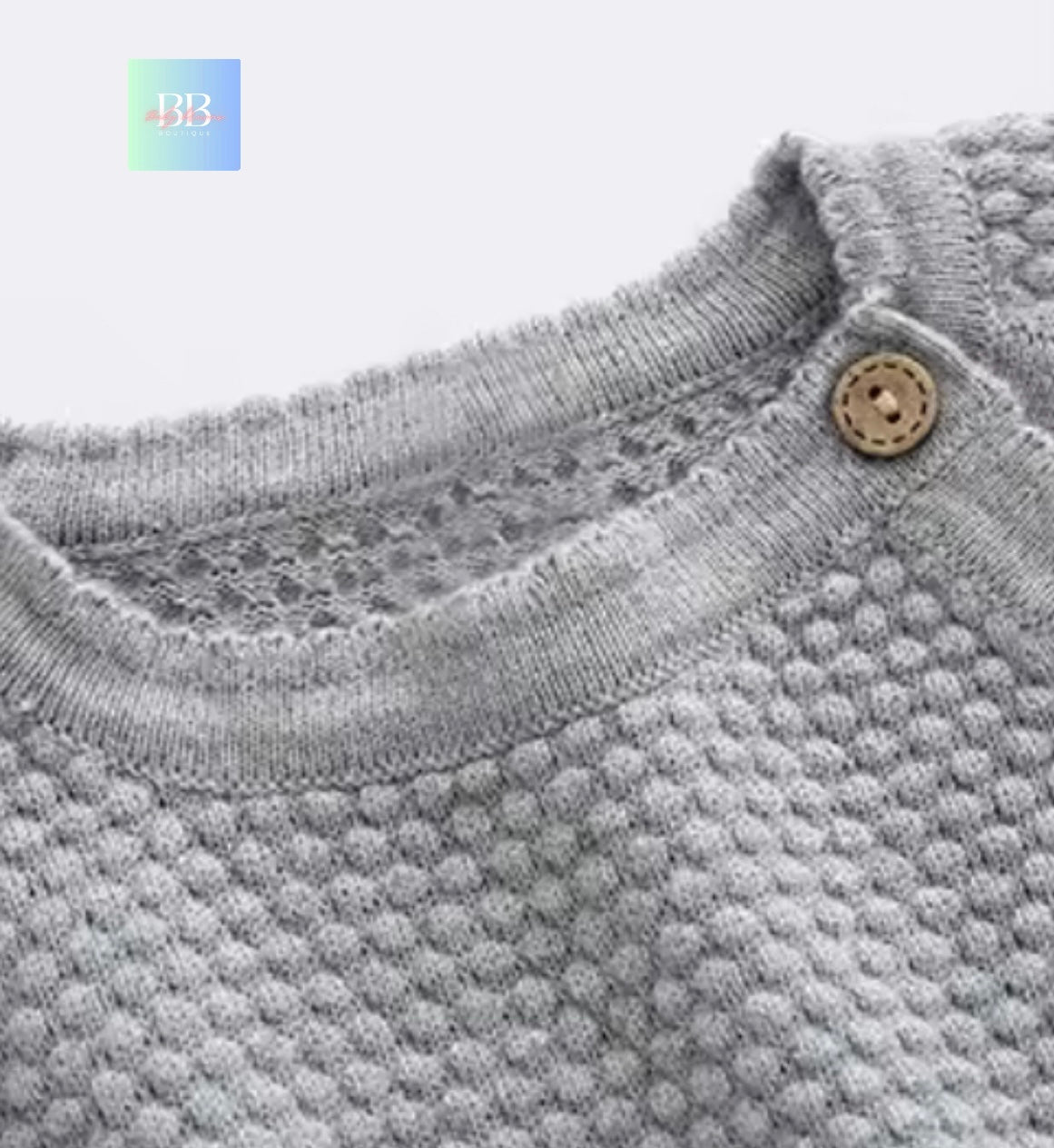 Close-up of a textured gray sweater with a button on a light gray background