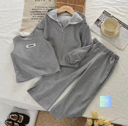 Gray children's outfit with vest, jacket, and pants on a white surface with newspaper and cup.