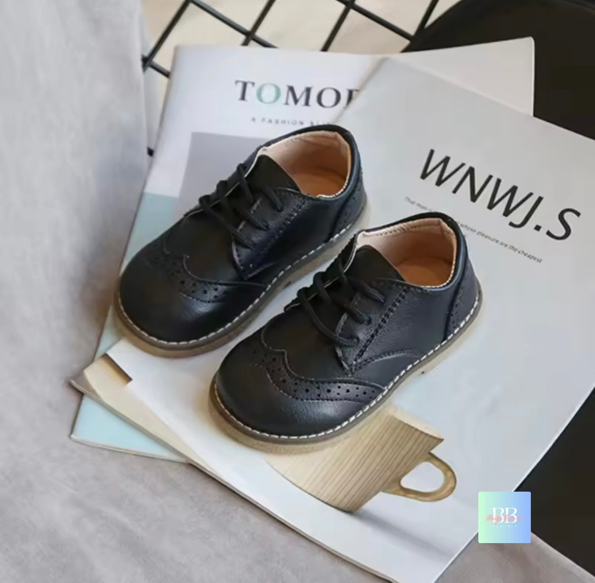 Black children's shoes on a magazine with visible text