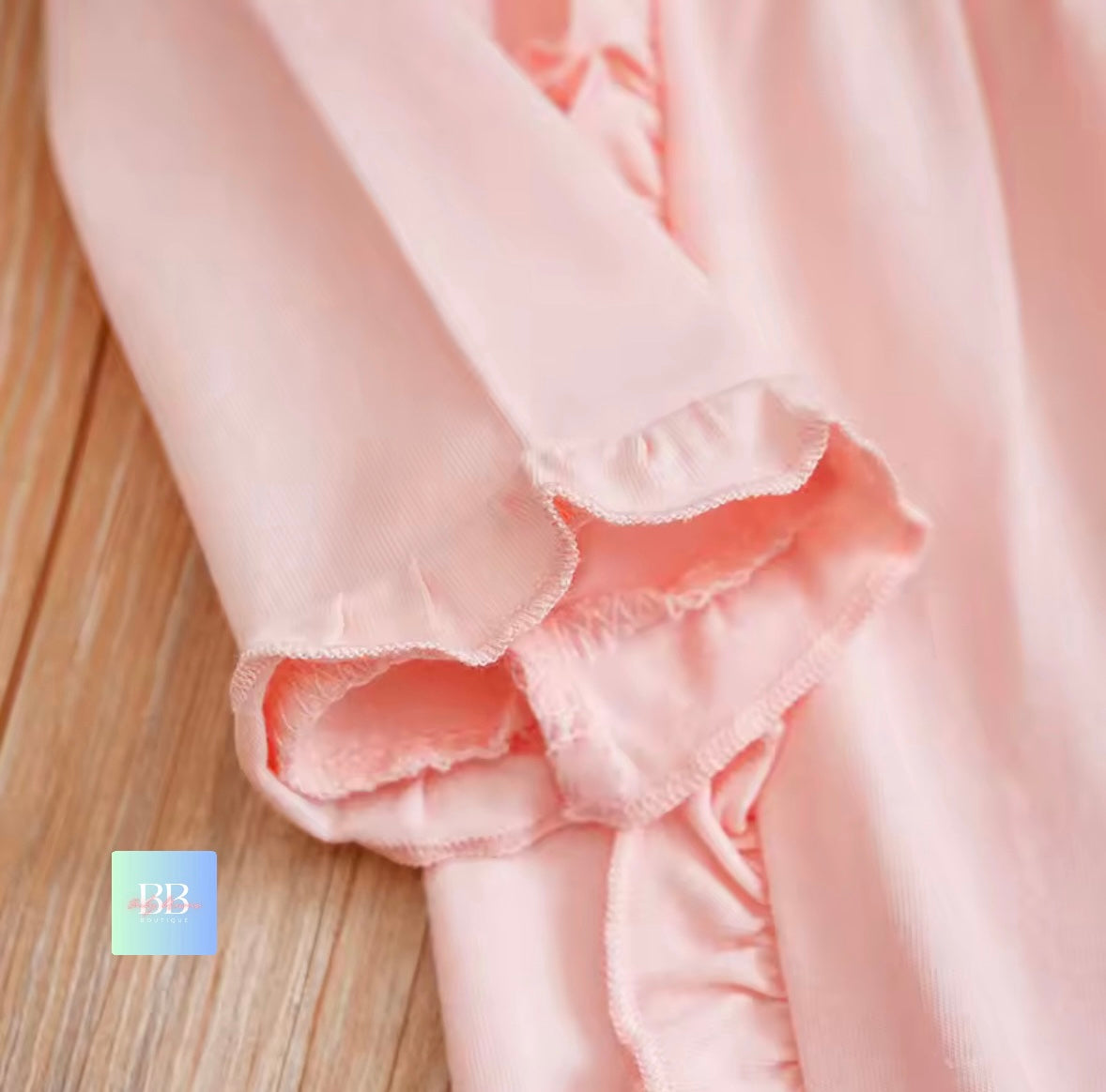 Close-up of pink fabric with ruffled edges on a wooden surface