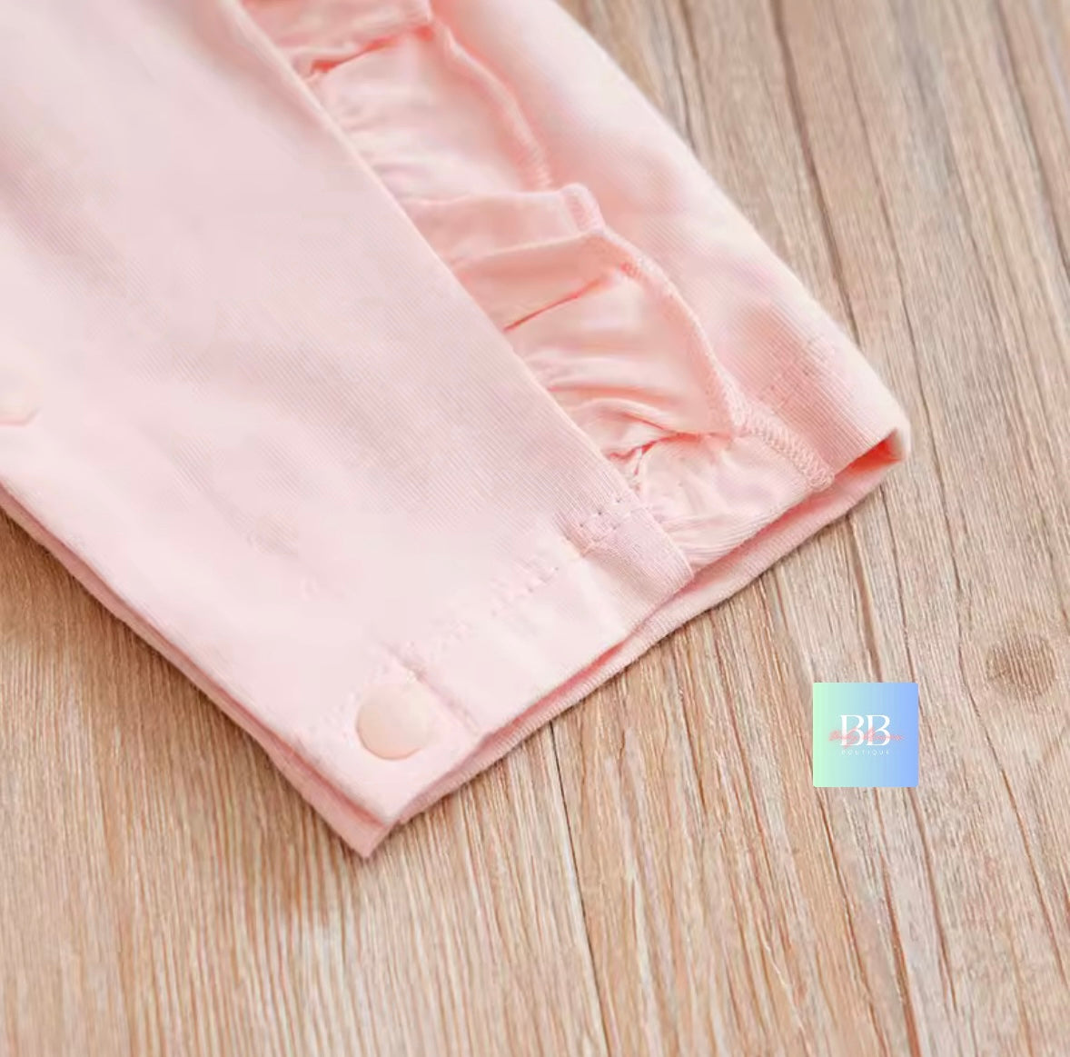 Pink fabric with ruffled edge on a wooden surface