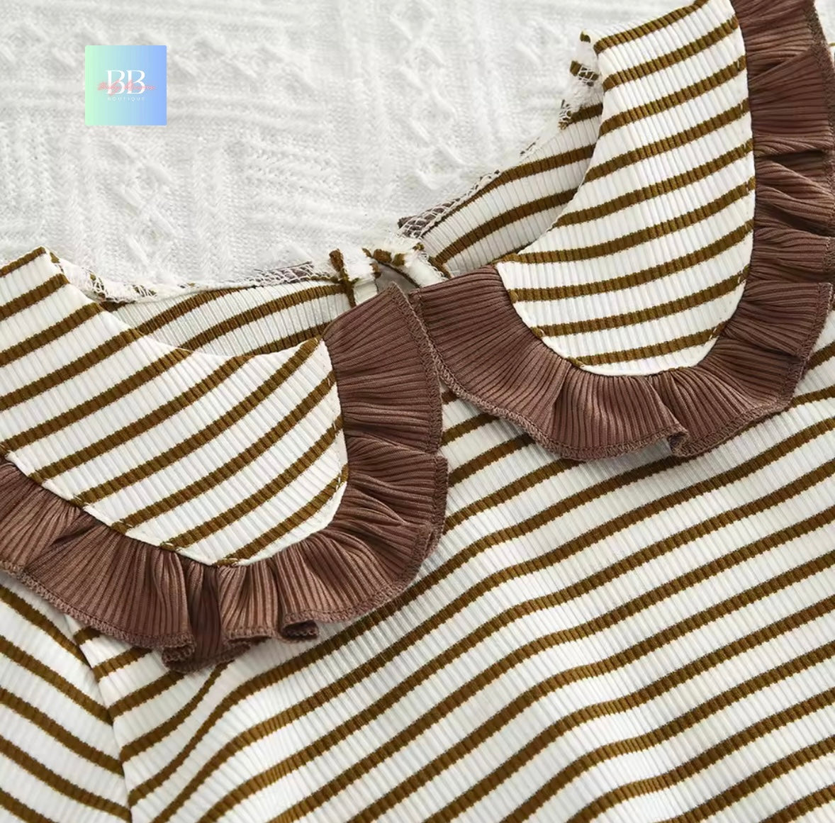 Brown and white striped fabric with ruffled collar on a textured background