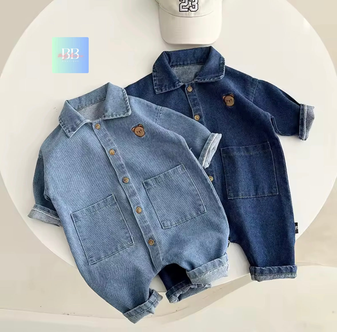 Two denim baby rompers on a white background with a visible brand logo.
