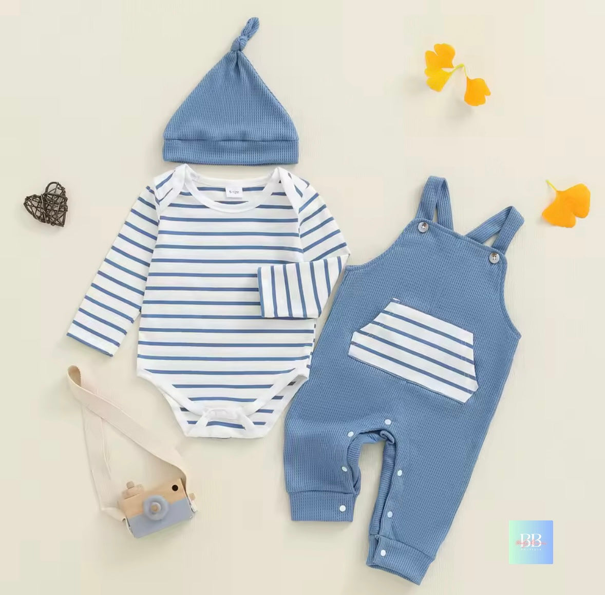 Baby outfit set with striped romper, blue overalls, and hat on a light background