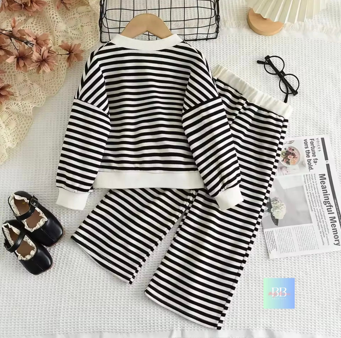 Black and white striped outfit with matching shoes on a textured surface.