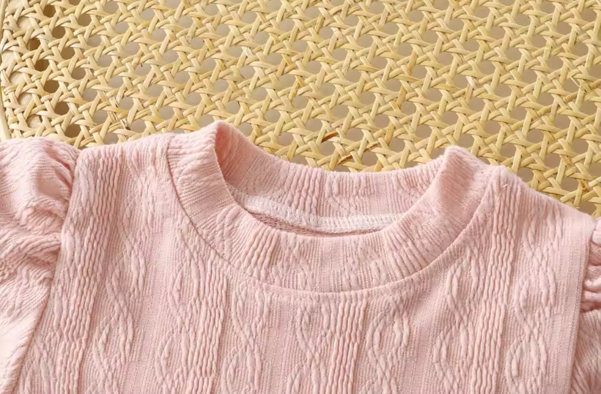 Close-up of a pink textured garment against a woven yellow background