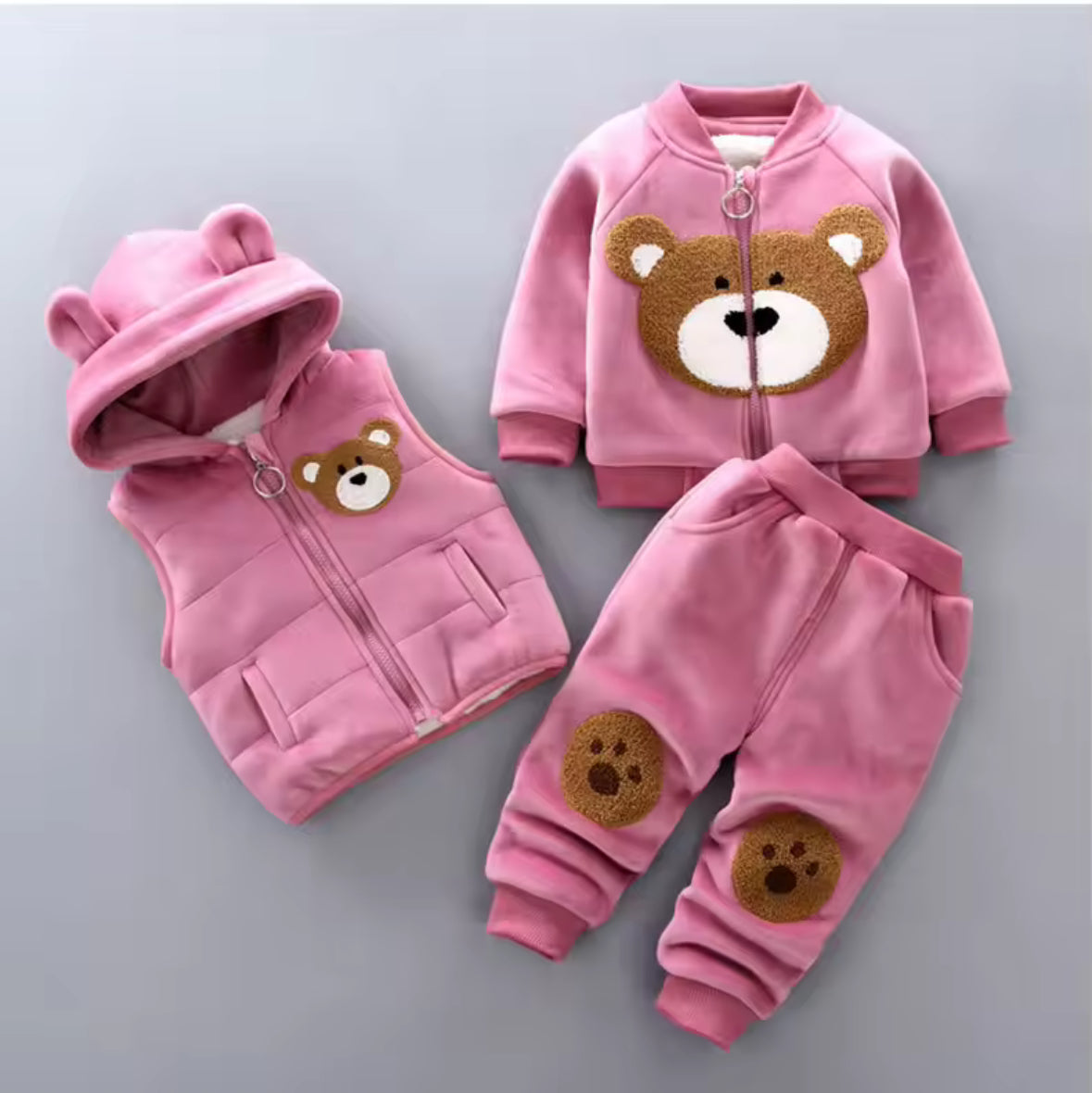 Pink children's outfit with bear designs on a gray background