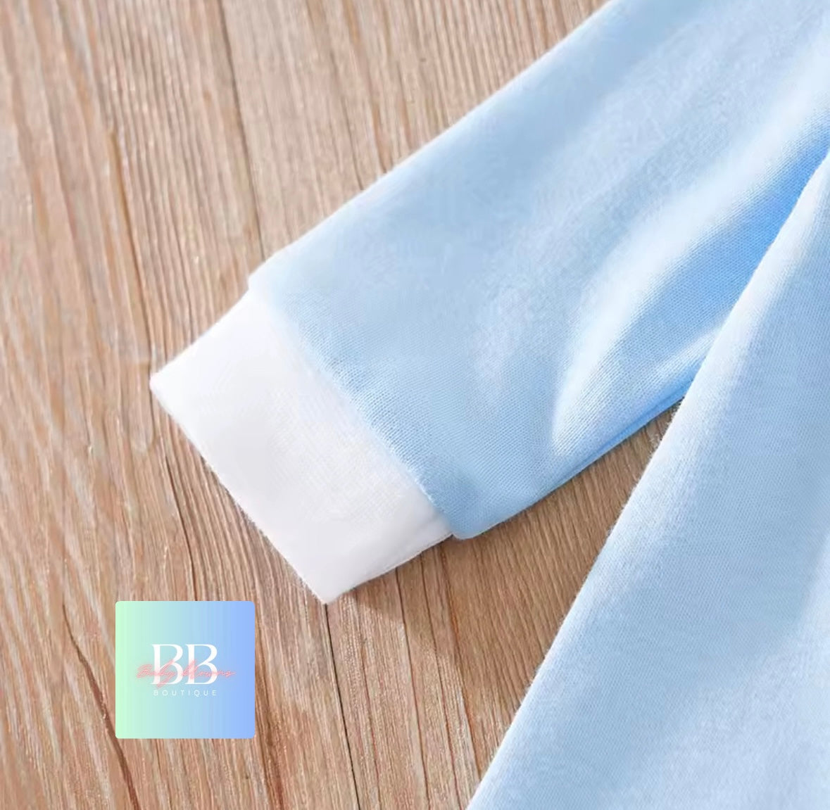 Light blue fabric on a wooden surface with a brand logo in the corner.