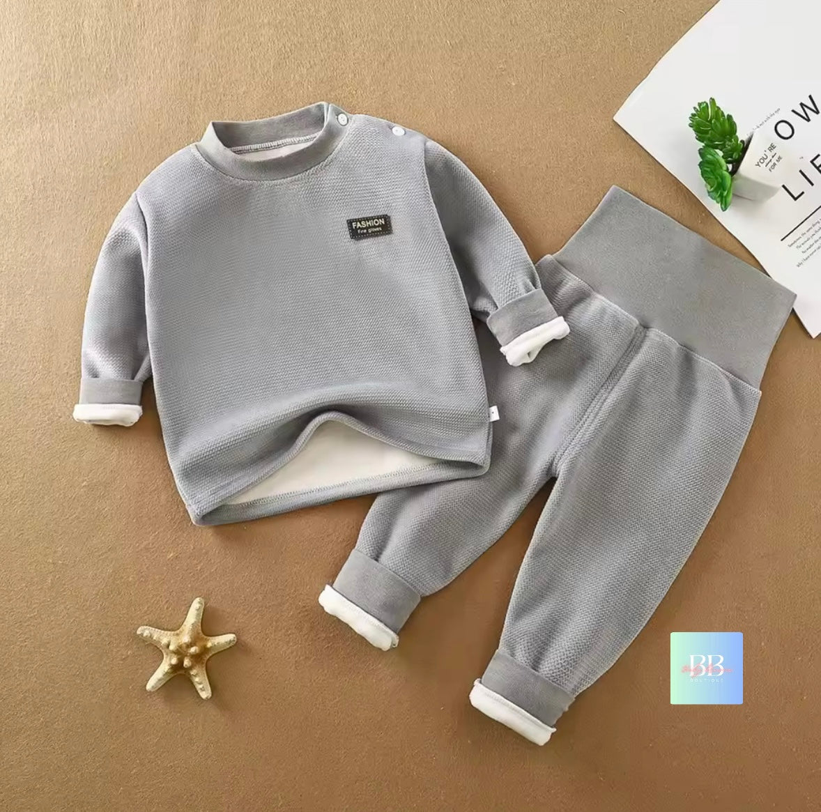 Children's gray outfit with white cuffs on a brown surface