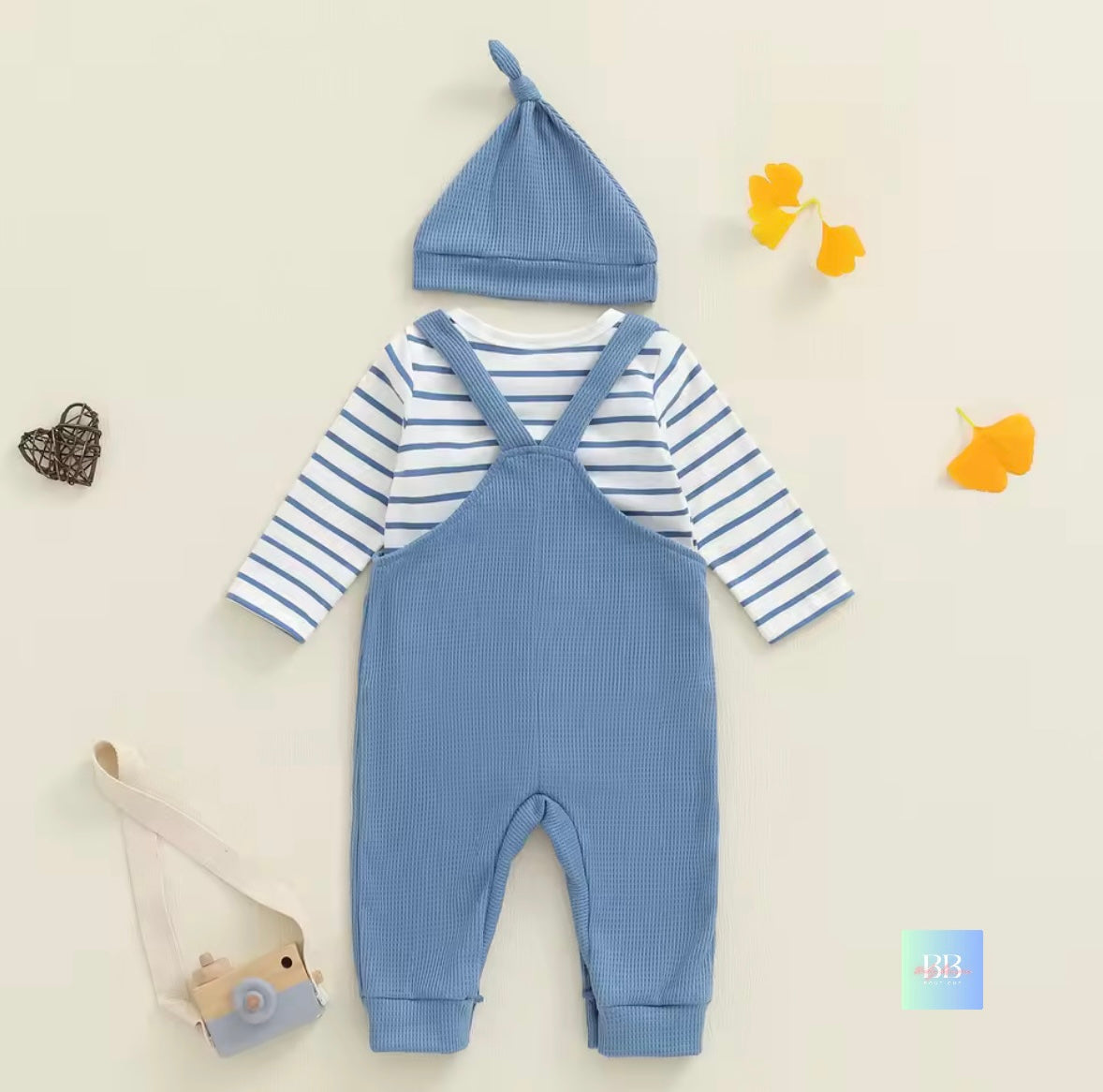 Baby outfit with blue romper, striped shirt, and hat on a light background