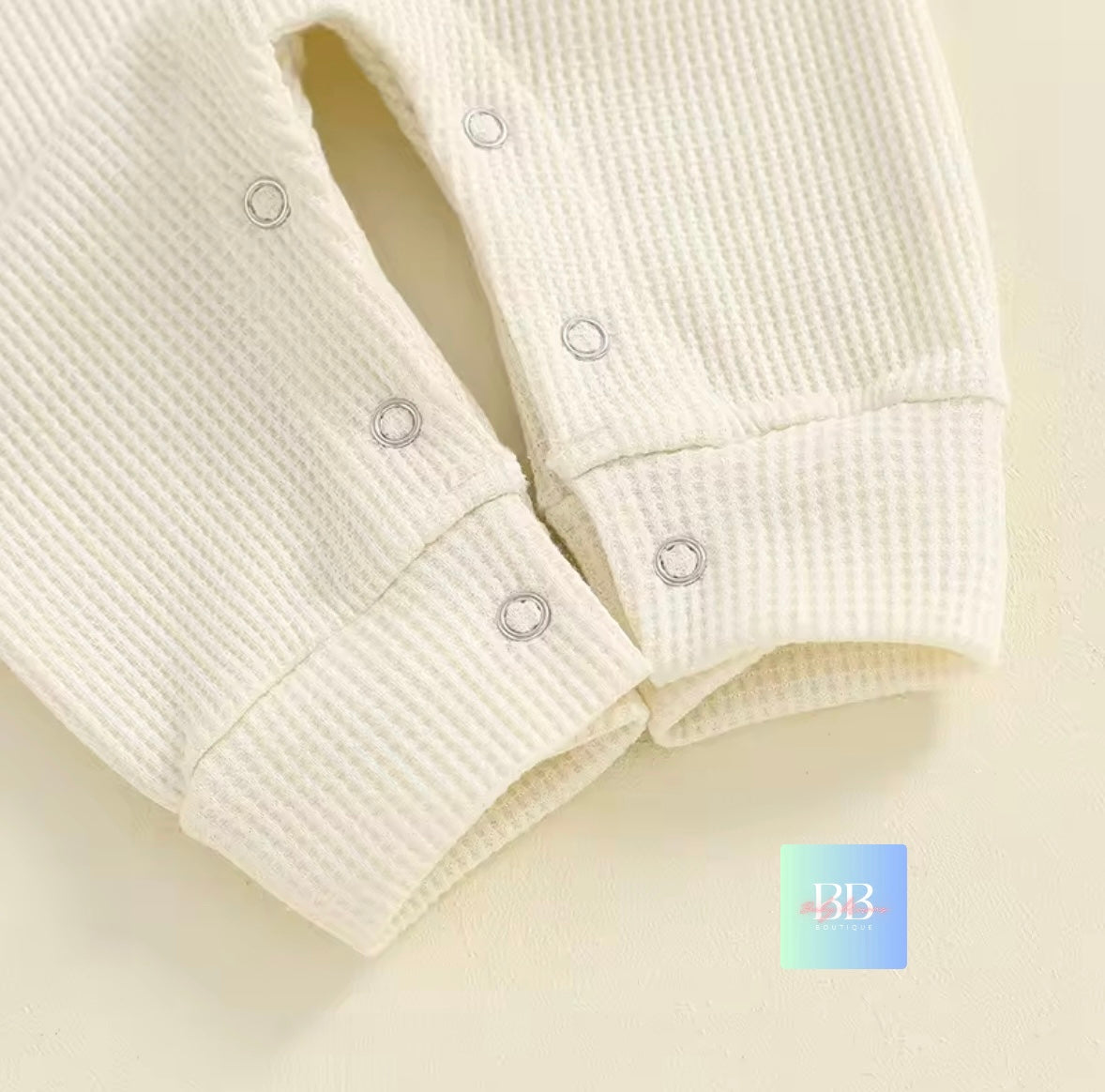 Close-up of a textured white garment with buttons on a light background