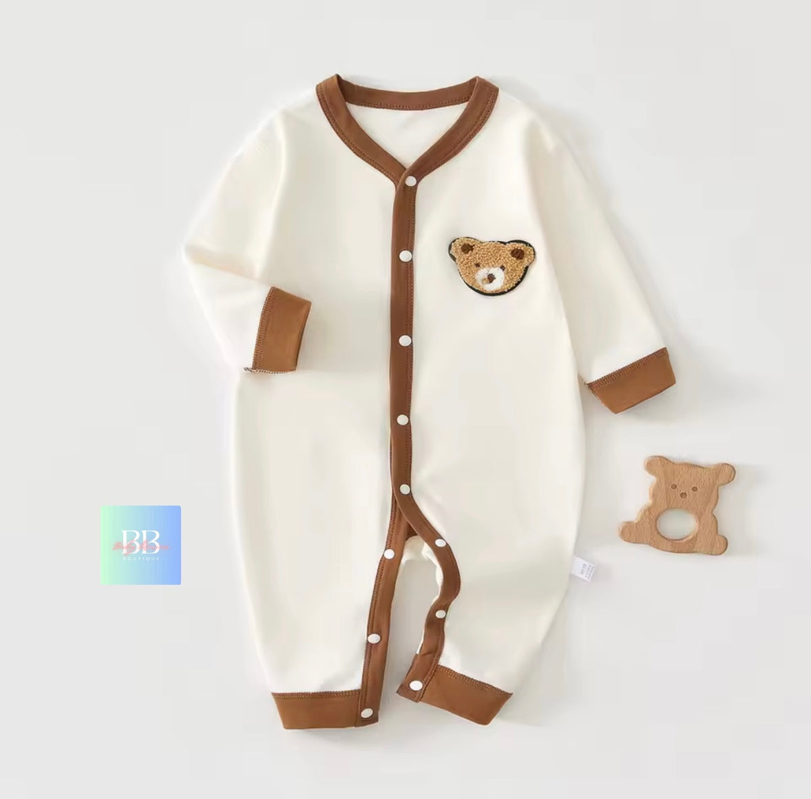 Baby onesie with bear design and wooden ring on a white background