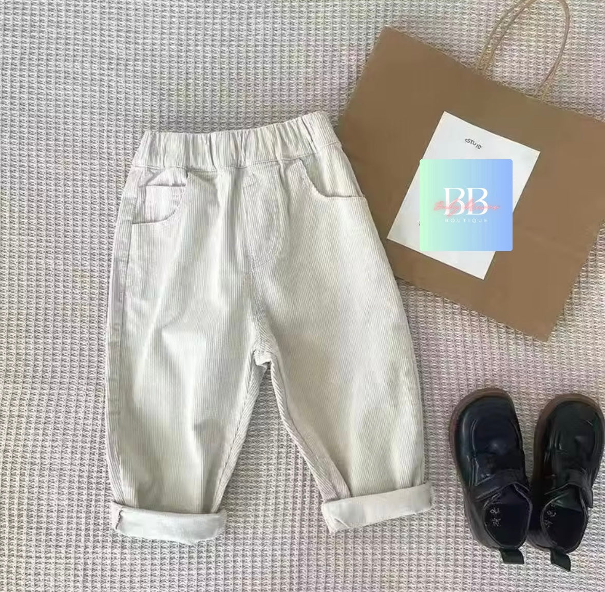 Light-colored pants with a brown bag and shoes on a textured surface