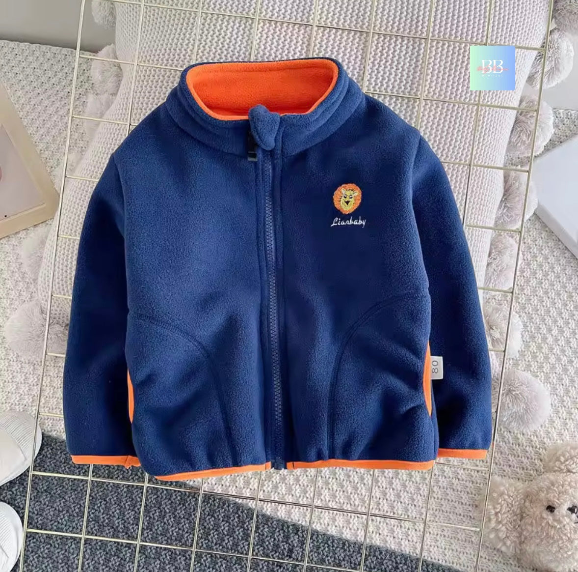 Blue children's jacket with orange lining on a tiled floor