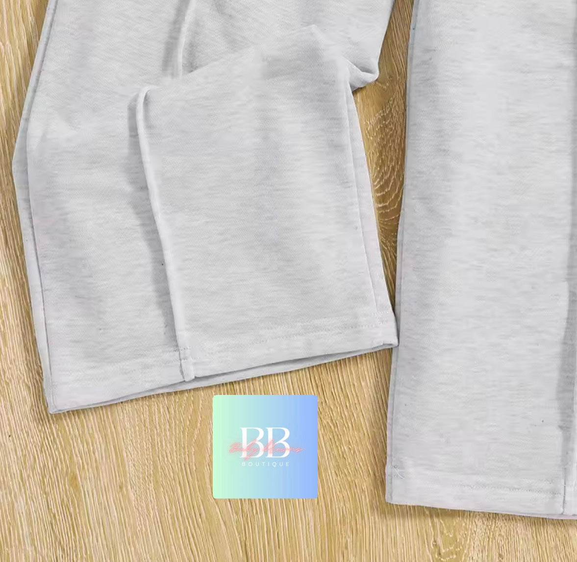 Gray fabric on a wooden surface with a brand logo in the corner.