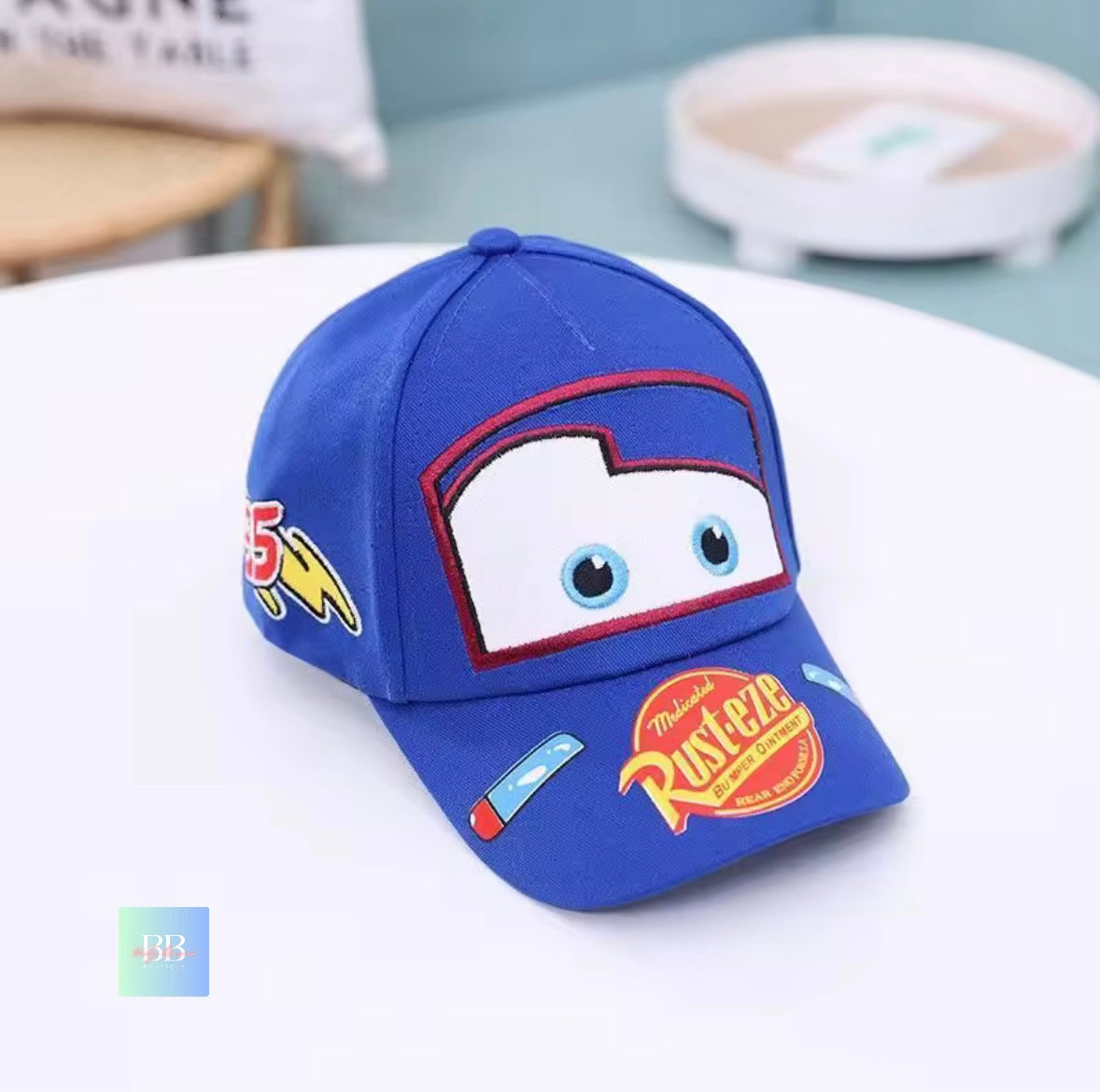 Blue children's cap with cartoon face design on a white surface