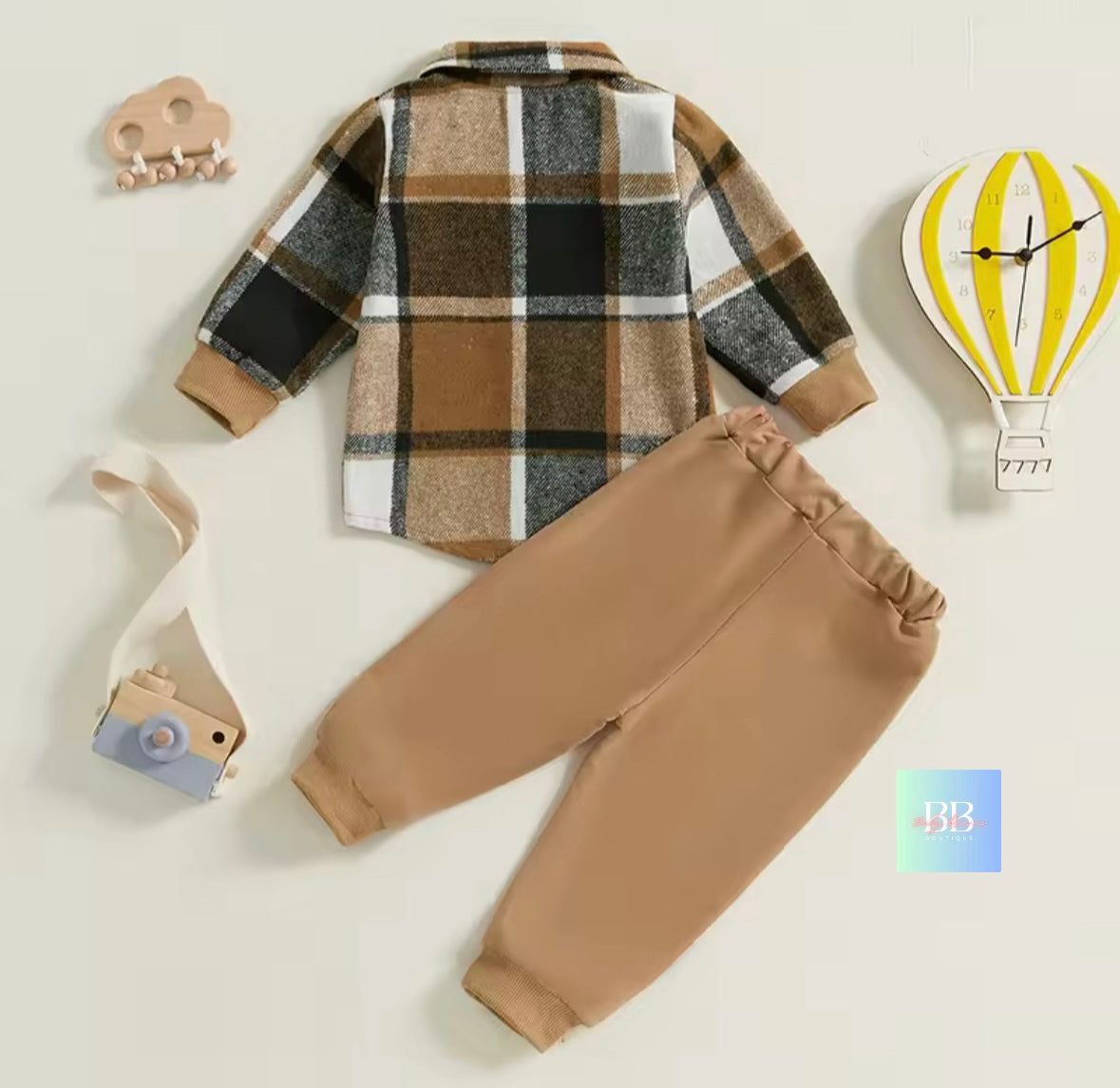 Plaid shirt and beige pants set on a light background with decorative items.