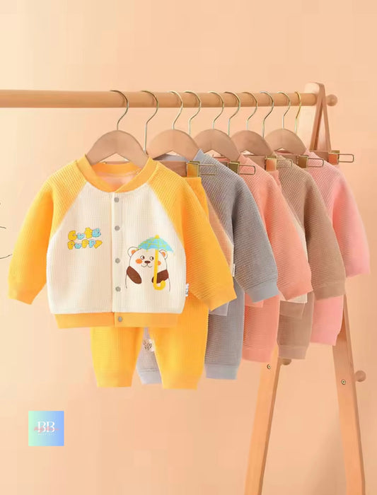 Children's clothing set with cartoon design on a wooden rack against a beige background