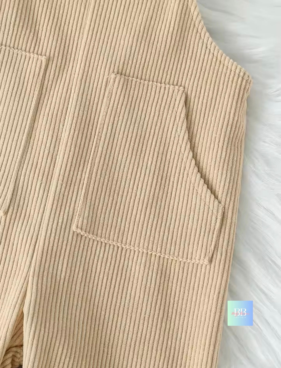 Close-up of beige corduroy pants with a pocket detail.