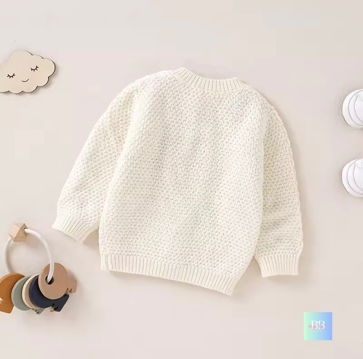 White knitted sweater on a light gray background with toys around