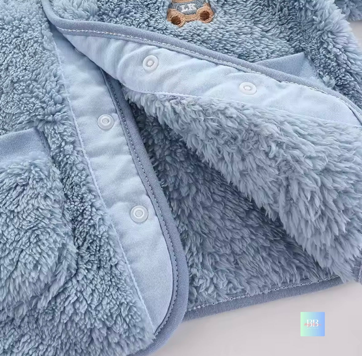 Close-up of a fluffy blue garment with buttons on a white background