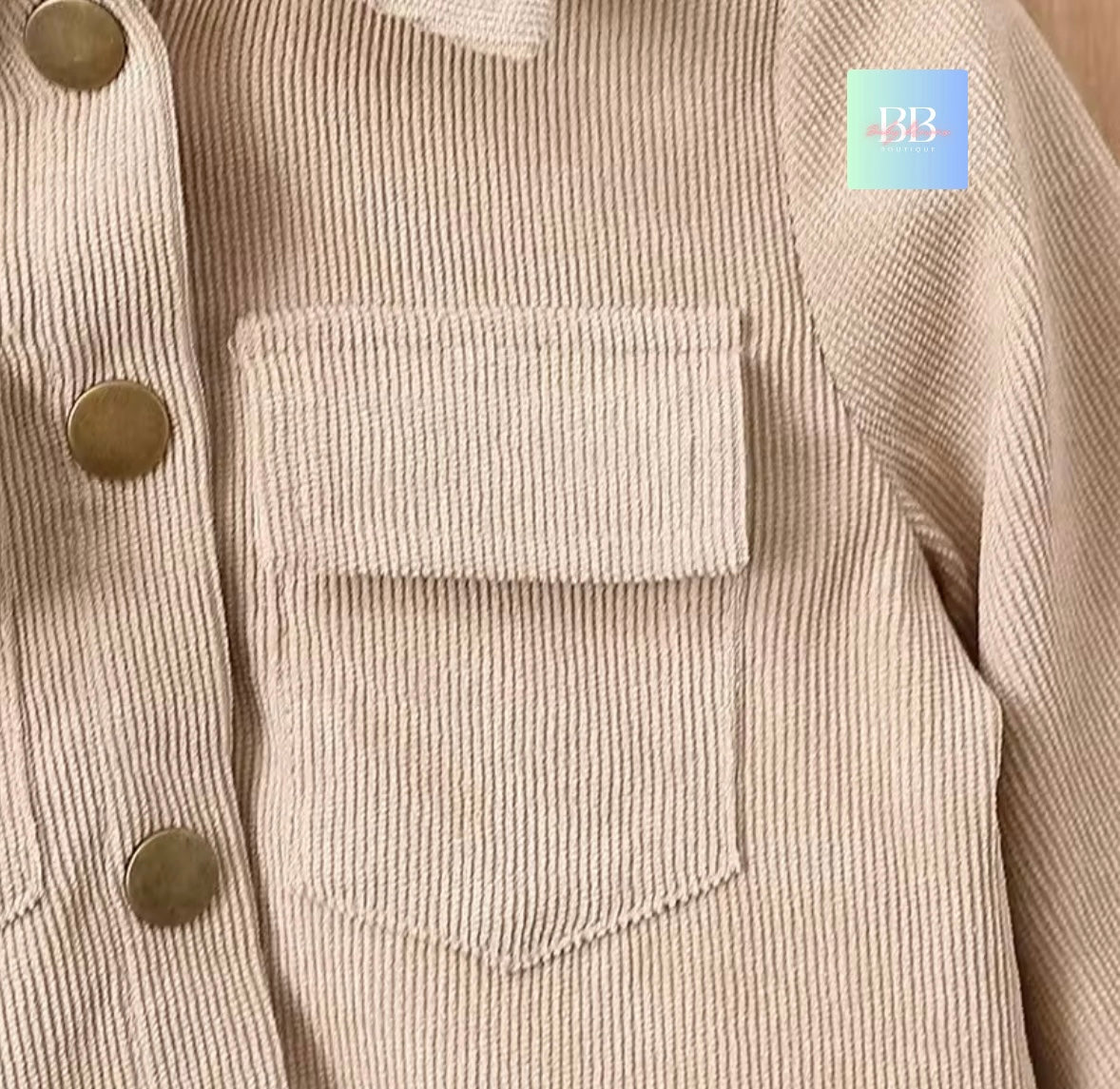 Close-up of a beige corduroy jacket with button details on a plain background