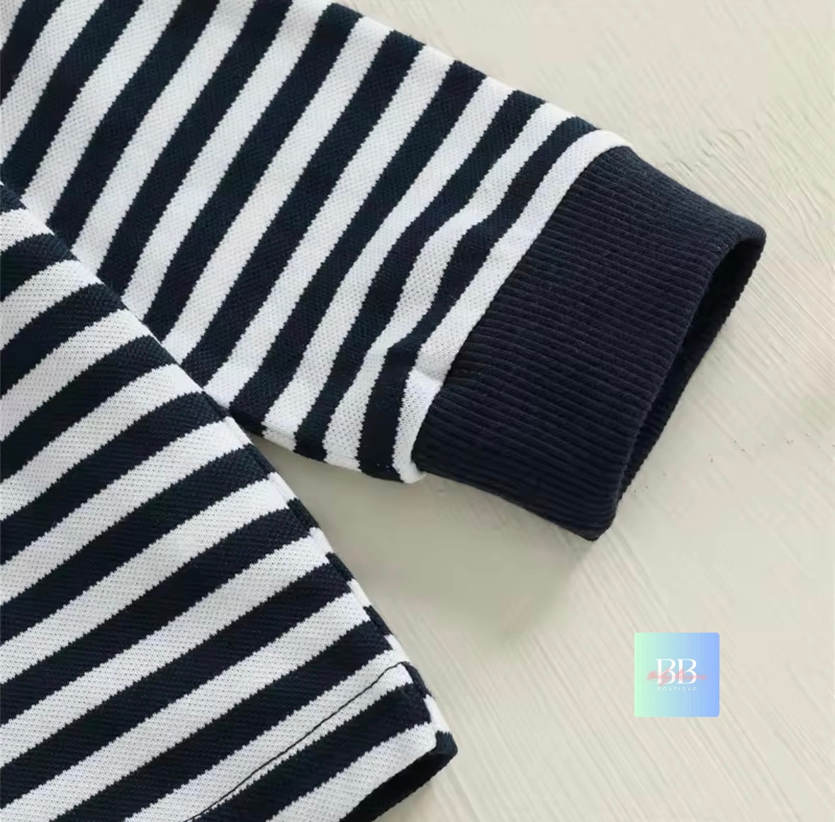 Black and white striped sweater on a light wooden surface