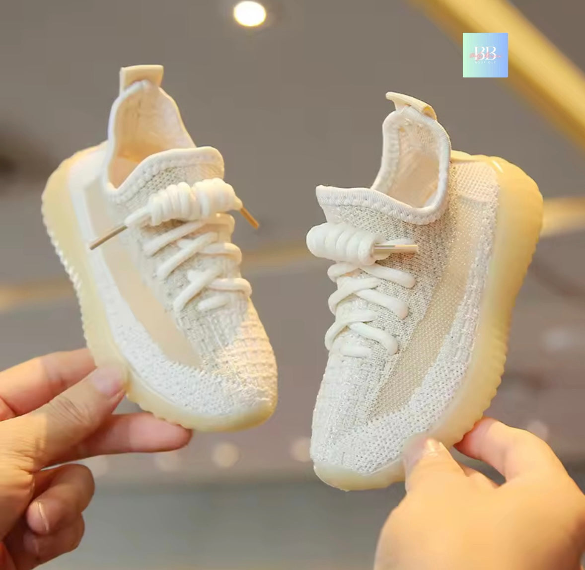 White sneakers held by two hands against a blurred background